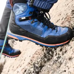 Close-up of a blue and black hiking boot with orange accents on a rocky surface.