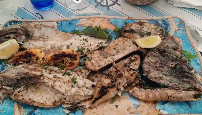 A platter of grilled fish and shrimp with lemon wedges and parsley.