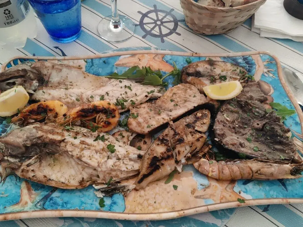 A platter of grilled fish and shrimp with lemon wedges and parsley.