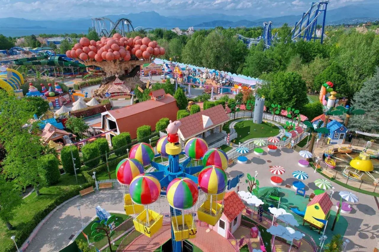 Un parco divertimenti colorato con giostre, alberi giganti e montagne russe. Forse la nuova gardaland attrazione 2026 è già qui!